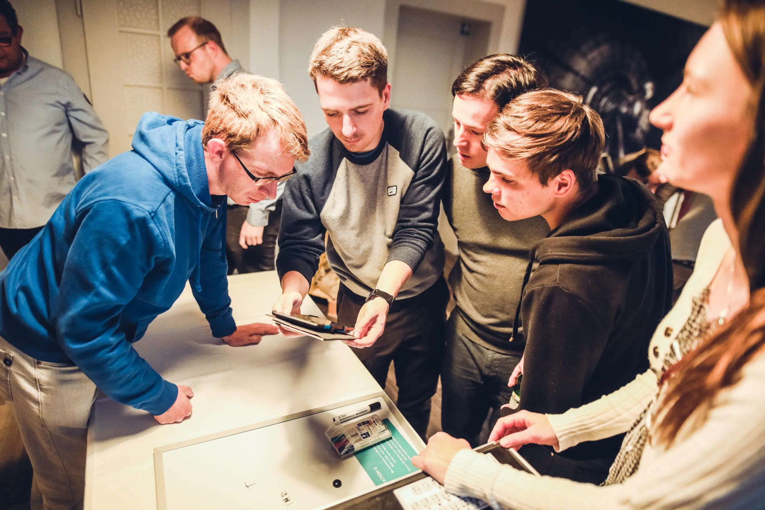 Escape Room+ für Firmen Kolleginnen und Kollegen beugen sich gemeinsam über einen Spieltisch im FORTNOXX® Escape Room+