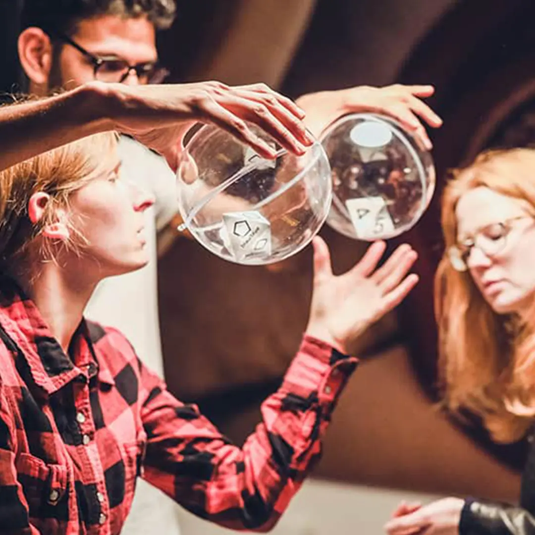 FORTNOXX® Escape Room+ Dresden Spielerinnen und Spieler greifen nach Würfeln in Plexiglaskugeln im FORTNOXX® Escape Room+